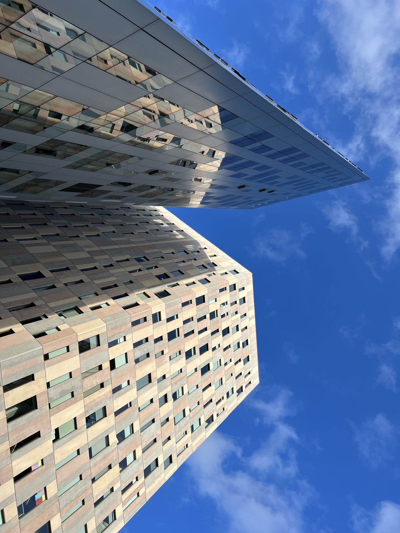A modern office tower seen from below against a blue sky in Barcelona