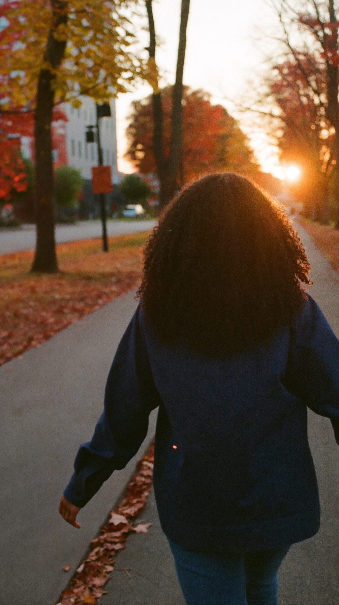 A student walking away from the camera through a sunlit courtyard, mid-stride