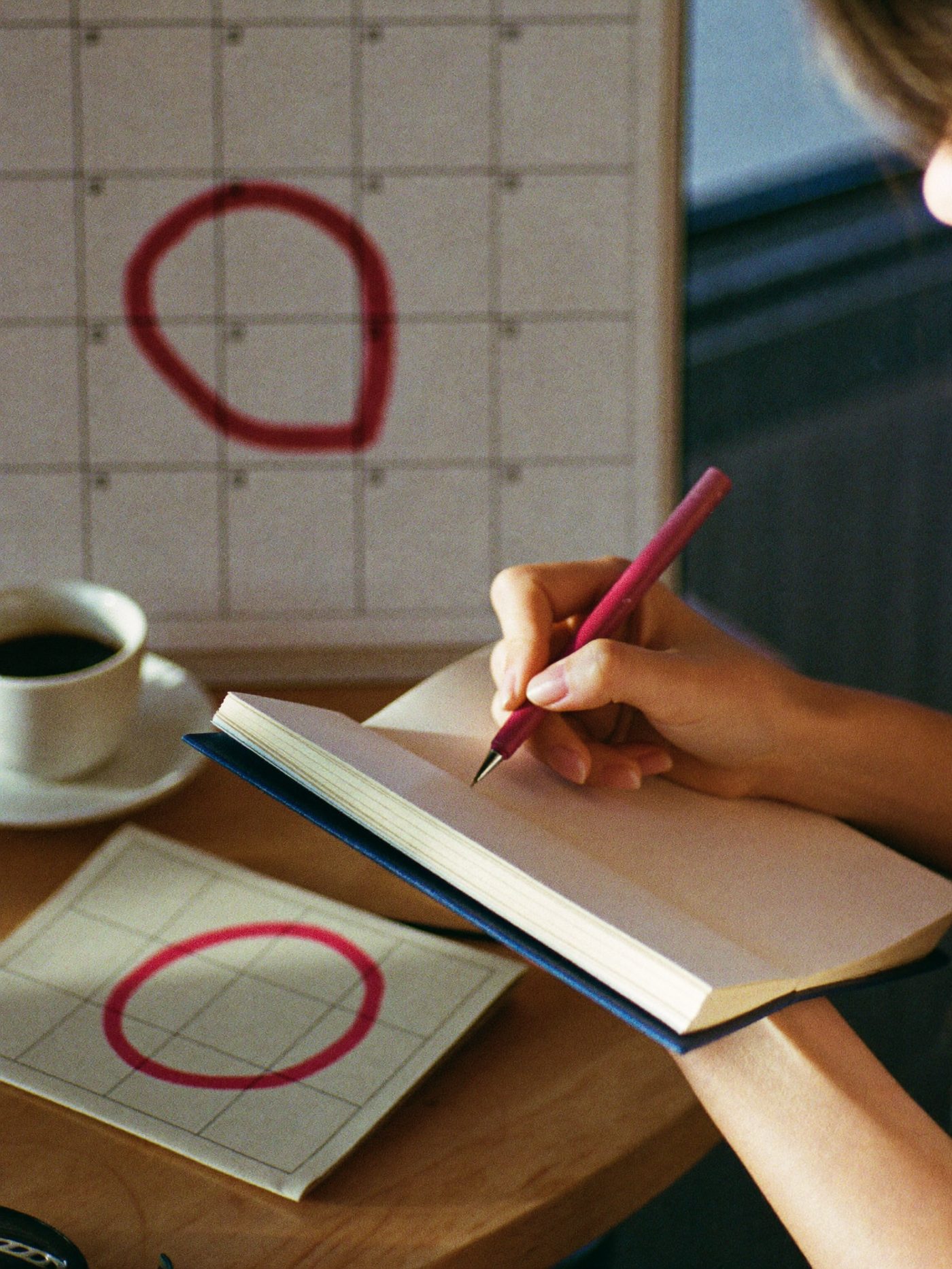 An open notebook beside a blank calendar grid with one date circled in red